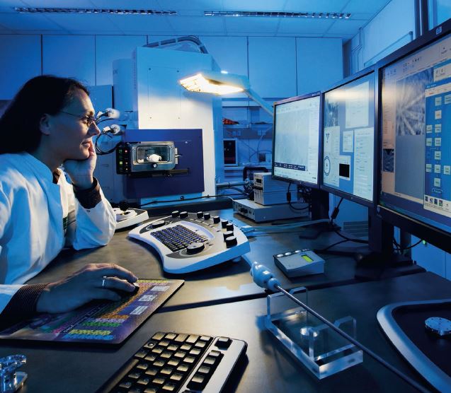 Frau arbeitet in einem Labor an einem Computer mit zwei Bildschirmen.
