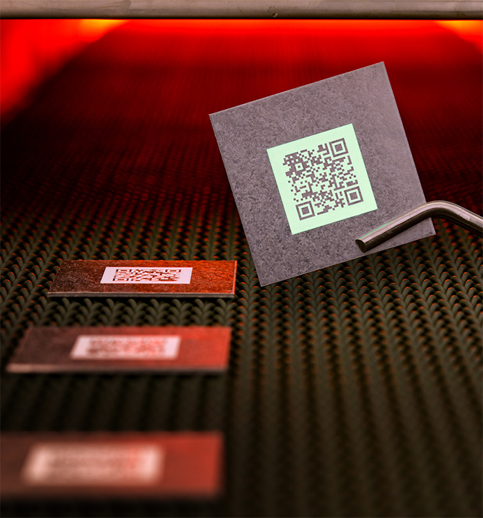 Hochtemperaturfähige Produktmarkierung in der Form eines QR-Codes auf Bauteil unter UV-Licht.