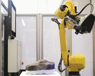 Ein Industrieroboter und davor liegt auf einem Tisch ein Gegenstand für die automatisierte Texturanalyse von CFK.